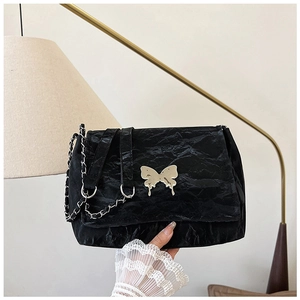 Close-up of black pleated shoulder bag with silver butterfly buckle and chain strap