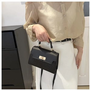 Detail view of the black crossbody bag featuring a golden twist lock and glitter patchwork