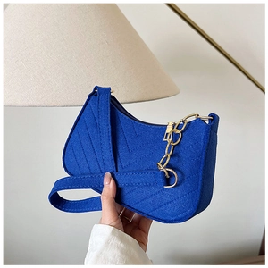 Detail of royal blue felt shoulder bag featuring V-shaped quilting and gold metal chain