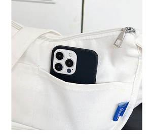 Détail du sac en toile blanche avec poche latérale et smartphone pour la dimension