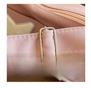 Détail de la bandoulière en tissu rose et de la boucle en métal doré clair du sac fourre-tout