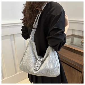 Detailed side view of silver metallic shoulder bag with pleated texture and tassel