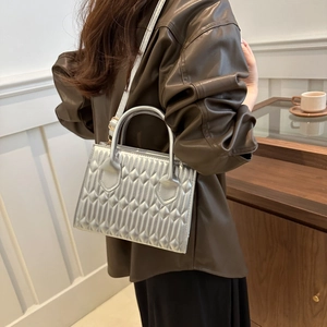 Silver metallic quilted tote bag with geometric pattern and top handles shown on model