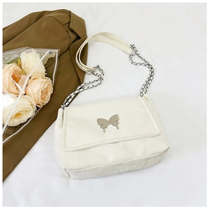 Detail view of cream shoulder bag with silver butterfly buckle and chain strap accents