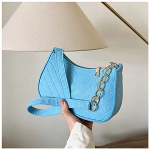 Detailed view of light blue felt shoulder bag with V-shaped stitching and gold chain strap
