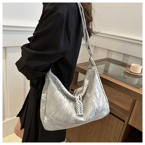 Detail showing the silver metallic crinkled texture and woven ball pendant of the large bag