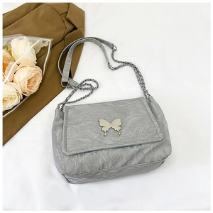 Detail of grey pleated shoulder bag with silver butterfly accent and chain strap