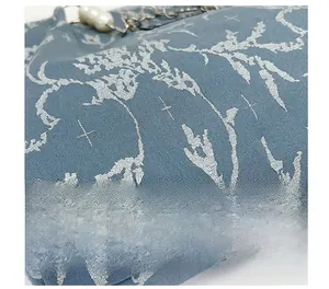 Détail du tissu jacquard bleu avec poignée en perles et bandoulière en chaîne argentée