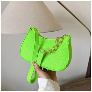 Detail of neon green felt shoulder bag with golden chain and zip closure