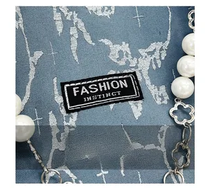 Détail du tissu bleu texturé et de l'étiquette Fashion Instinct sur le sac à main