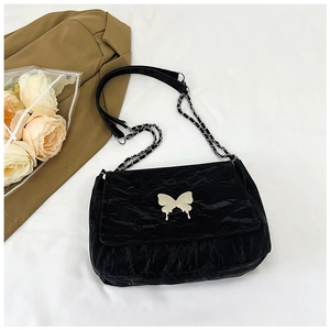 Detail of black pleated shoulder bag with silver butterfly buckle and chain strap