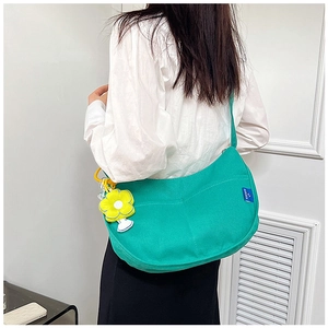 Détail d'un sac cabas en toile vert vif avec un pendentif fleur jaune et une étiquette logo