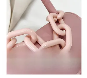 Détail du sac en similicuir rose avec poignée en chaîne de résine et texture lisse