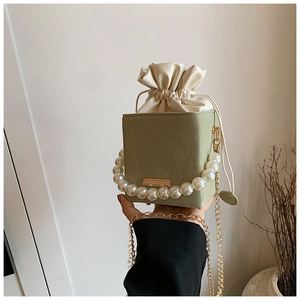 Detail of light green cube bag with pearl handle and drawstring inner lining