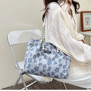 Détail du sac cabas en toile florale avec poignée en perles et étiquette mode instinct
