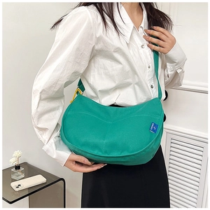 Détail d'un sac demi-lune en toile verte avec l'étiquette de marque bleue SORAKA