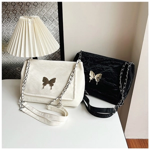 Close-up of butterfly metal buckle and chain strap on stylish faux leather shoulder bag