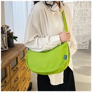 Détail du sac bandoulière en toile vert vif avec étiquette tissée SORAKA bleue et coutures
