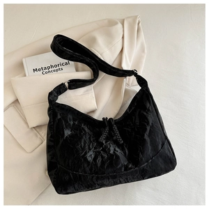 Close-up of black pleated texture shoulder bag with dual zippers and woven pulls