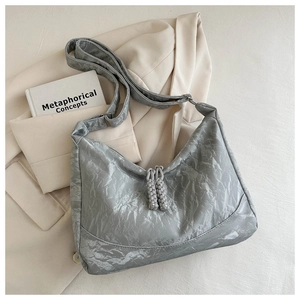 Close-up of metallic grey pleated shoulder bag with long tassel zippers on a blazer