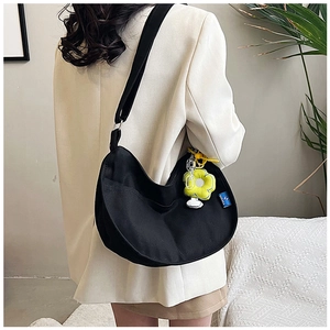 Détail du sac croissant en toile noire avec bandoulière réglable et breloque fleurie