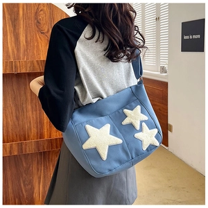 Sac cabas en toile bleue avec écussons étoiles blanches porté en scène lifestyle
