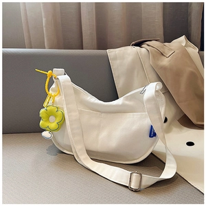 Détail du sac demi-lune en toile blanche avec charm tournesol et bandoulière réglable
