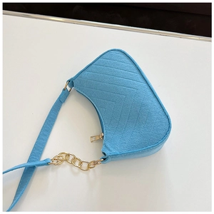 Detail of light blue felt baguette bag featuring V-shaped quilting and gold chain strap