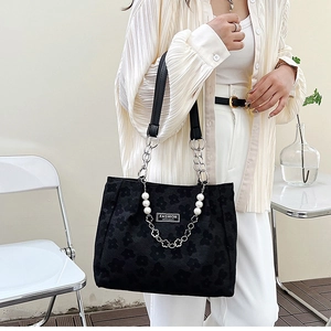 Détail du sac cabas en jacquard noir avec motif floral et chaîne décorative en perles