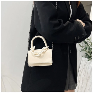 Détail du mini sac crème avec chaîne en résine et bandoulière argentée sur blazer