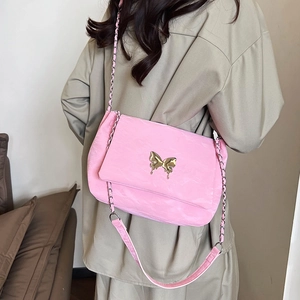 Pink shoulder bag with golden butterfly buckle and chain strap worn by a model