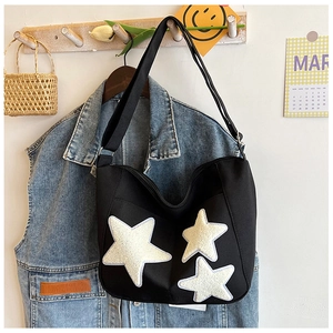 Détail du sac hobo en toile noire avec étoiles en peluche blanches et large sangle