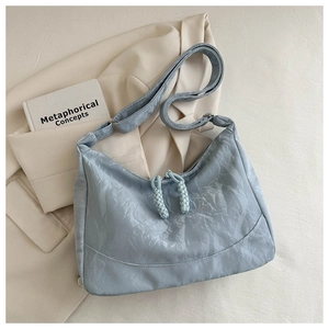 Detail of light blue shoulder bag with pleated fabric texture and double zippers