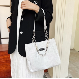 Sac cabas jacquard blanc avec chaîne de perles porté par mannequin en blazer noir