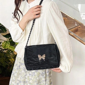 Chic black butterfly chain shoulder bag with crinkled texture in an elegant indoor setting