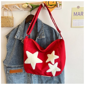 Détail du sac cabas en toile rouge avec étoiles en peluche blanches et fermeture éclair