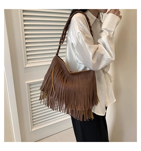 Detail of dark brown leather handbag with bohemian fringe and braided shoulder strap