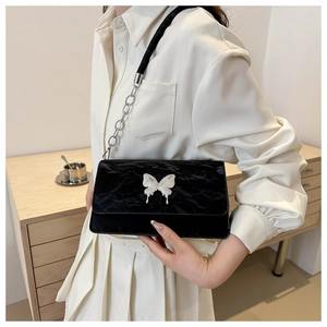 Close-up of black pleated shoulder bag with silver butterfly metal buckle and chain strap