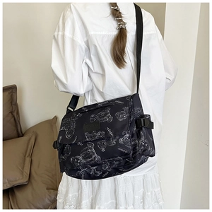 Close-up of black nylon messenger bag featuring white bear print and adjustable strap