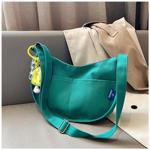 Détail du sac hobo en toile verte avec poches contrastées et breloque tournesol