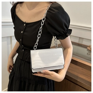 Close-up of white crocodile pattern shoulder bag with a bold silver chain metal strap