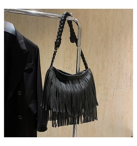 Detail of black pebbled leather shoulder bag with long tassels and woven strap