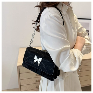 Detailed close-up of a black textured shoulder bag with a silver butterfly clasp buckle