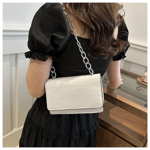 Detail of white crocodile texture crossbody bag with thick silver chain on model