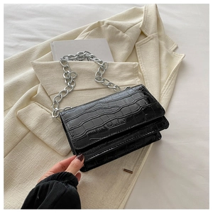 Close-up of black crocodile embossed small square bag with bold silver chain detail