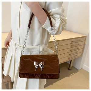 Detail of a brown crinkle leather shoulder bag featuring a silver butterfly buckle