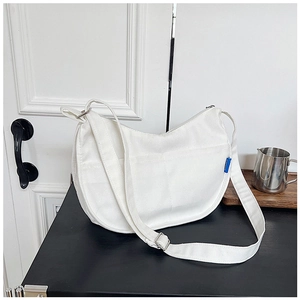 Détail de la bandoulière en toile réglable et de la boucle en métal argenté du sac blanc