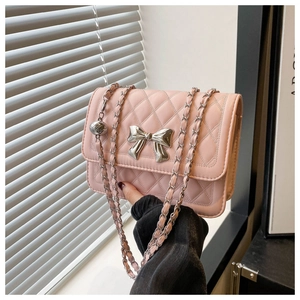 Detail of pink quilted shoulder bag with silver metal bow and chain strap accent