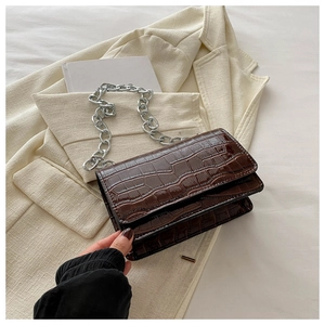 Detailed view of dark brown faux crocodile leather cross-body bag with thick silver chain