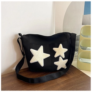 Détail du sac fourre-tout en toile noire avec trois écussons étoiles et bandoulière large